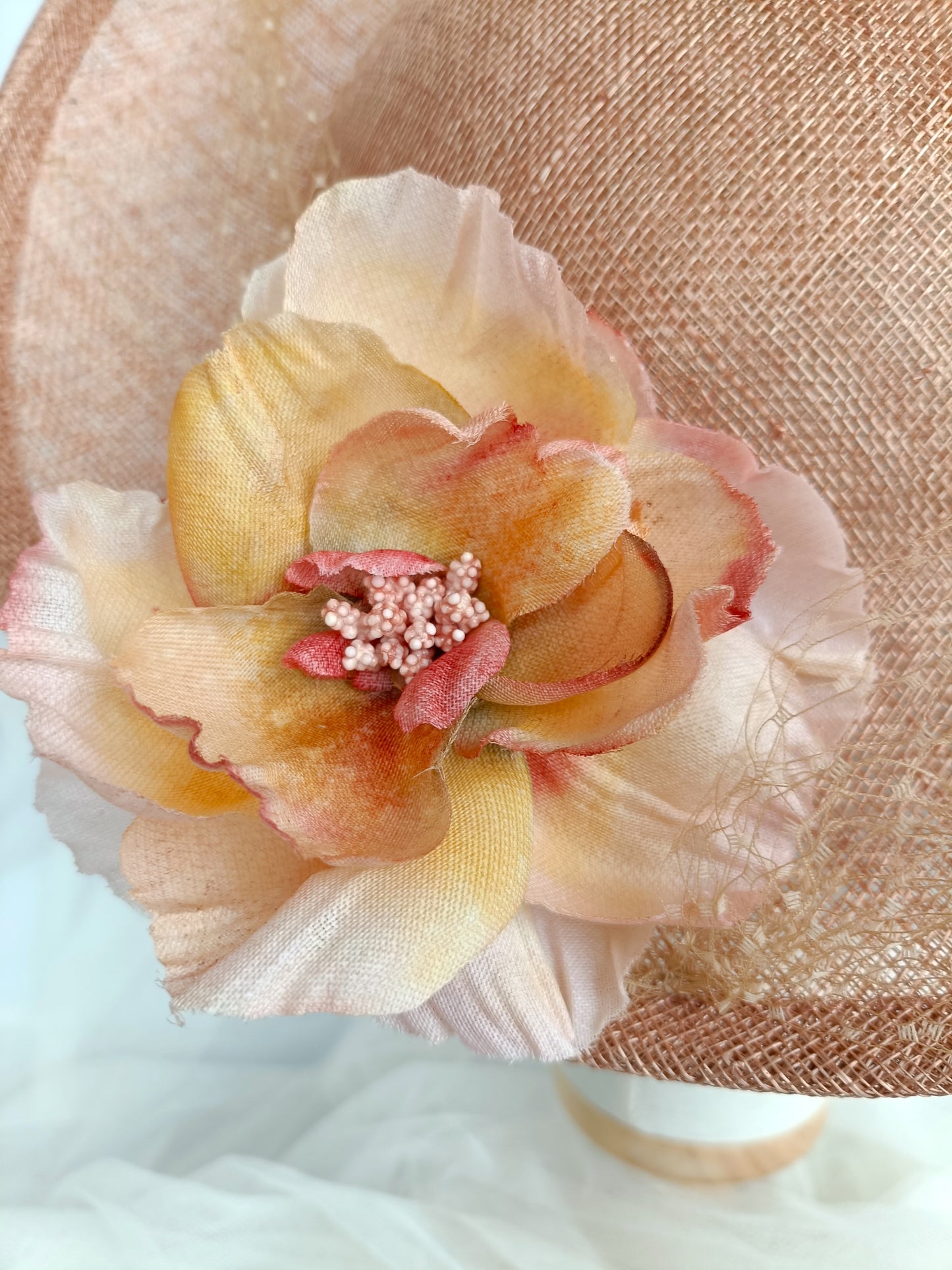 Tocado pamela de invitada en sinamay snaranjado, flores de seda azules y amarillas, con velo decorativo, elegante y colorido para boda.a