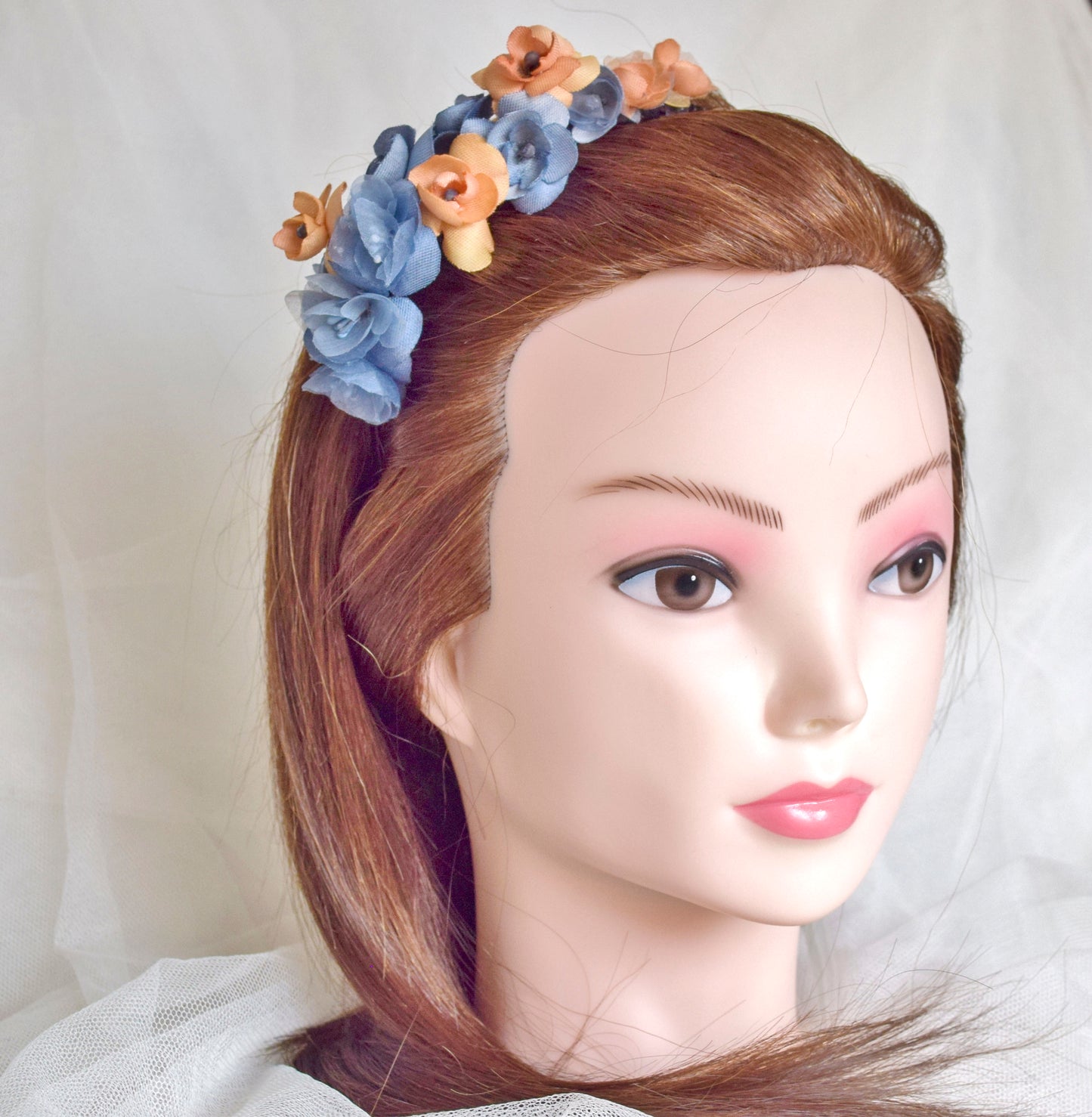 Diadema de flores de seda en azul y naranja, diseño elegante y romántico para invitada de boda o evento especial.