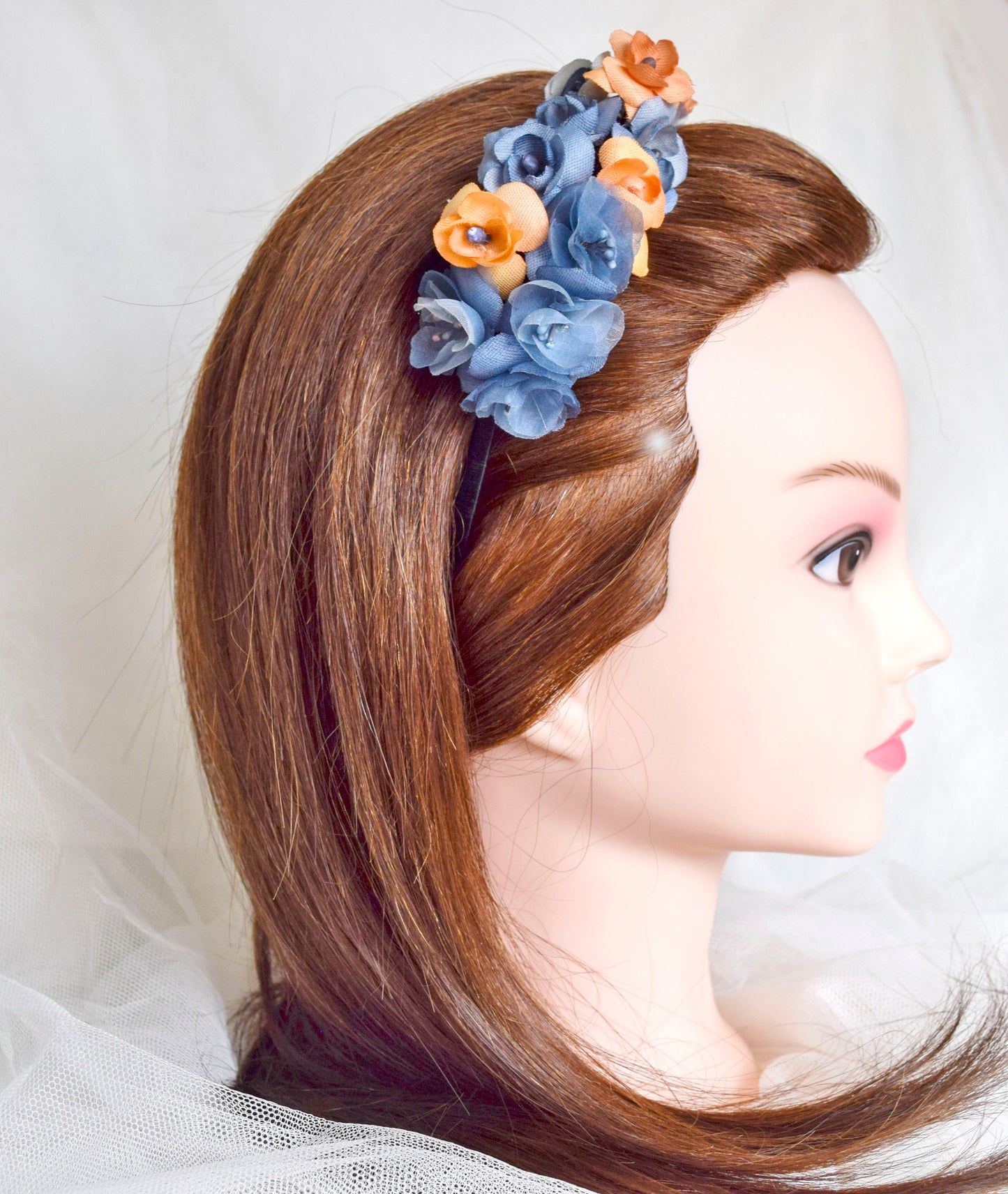 Diadema de flores de seda en azul y naranja, diseño elegante y romántico para invitada de boda o evento especial.