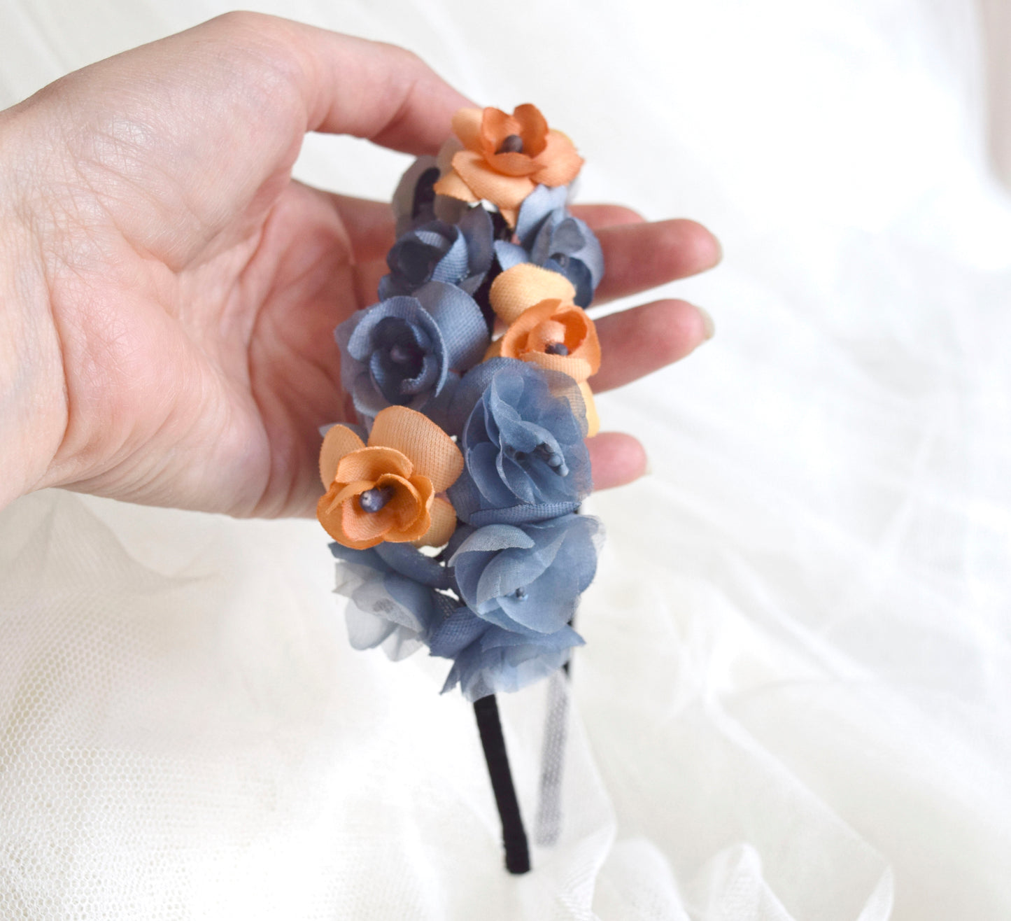 Diadema de flores de seda en azul y naranja, diseño elegante y romántico para invitada de boda o evento especial.