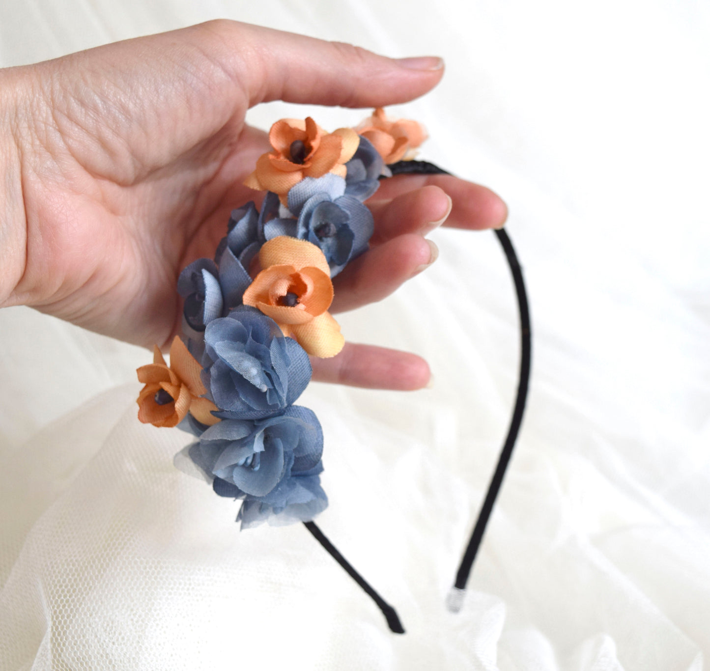Diadema de flores de seda en azul y naranja, diseño elegante y romántico para invitada de boda o evento especial.