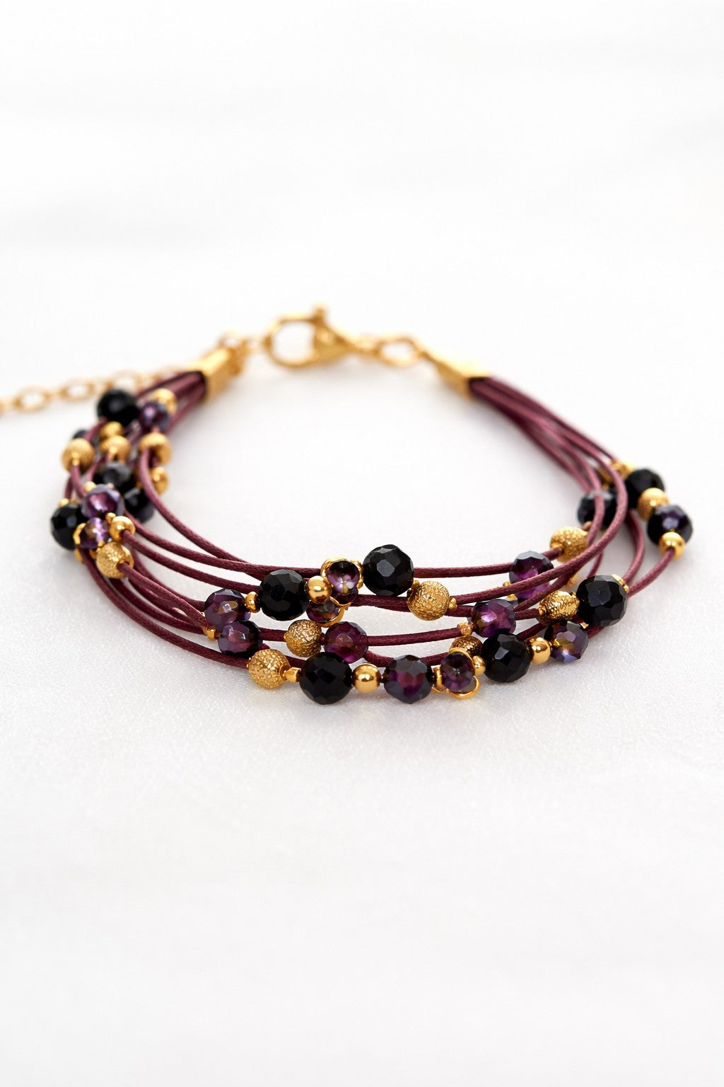 Pulsera granate de lino con cristal y acero dorado.