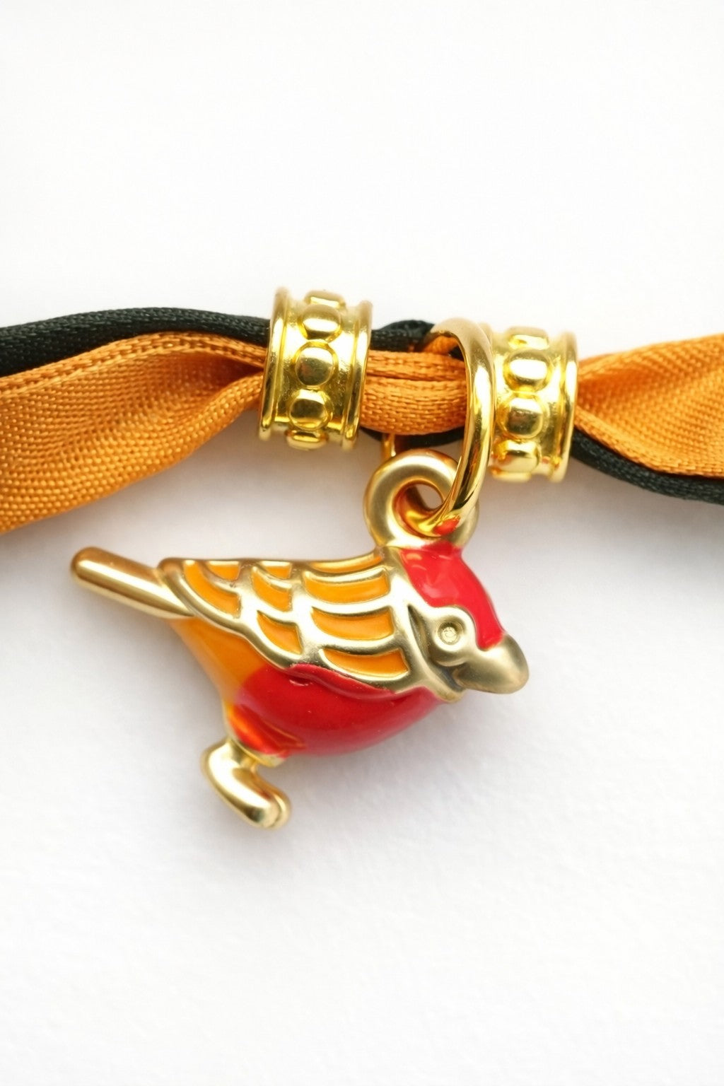 Pulsera de seda verde y mostaza con pajarita esmaltada