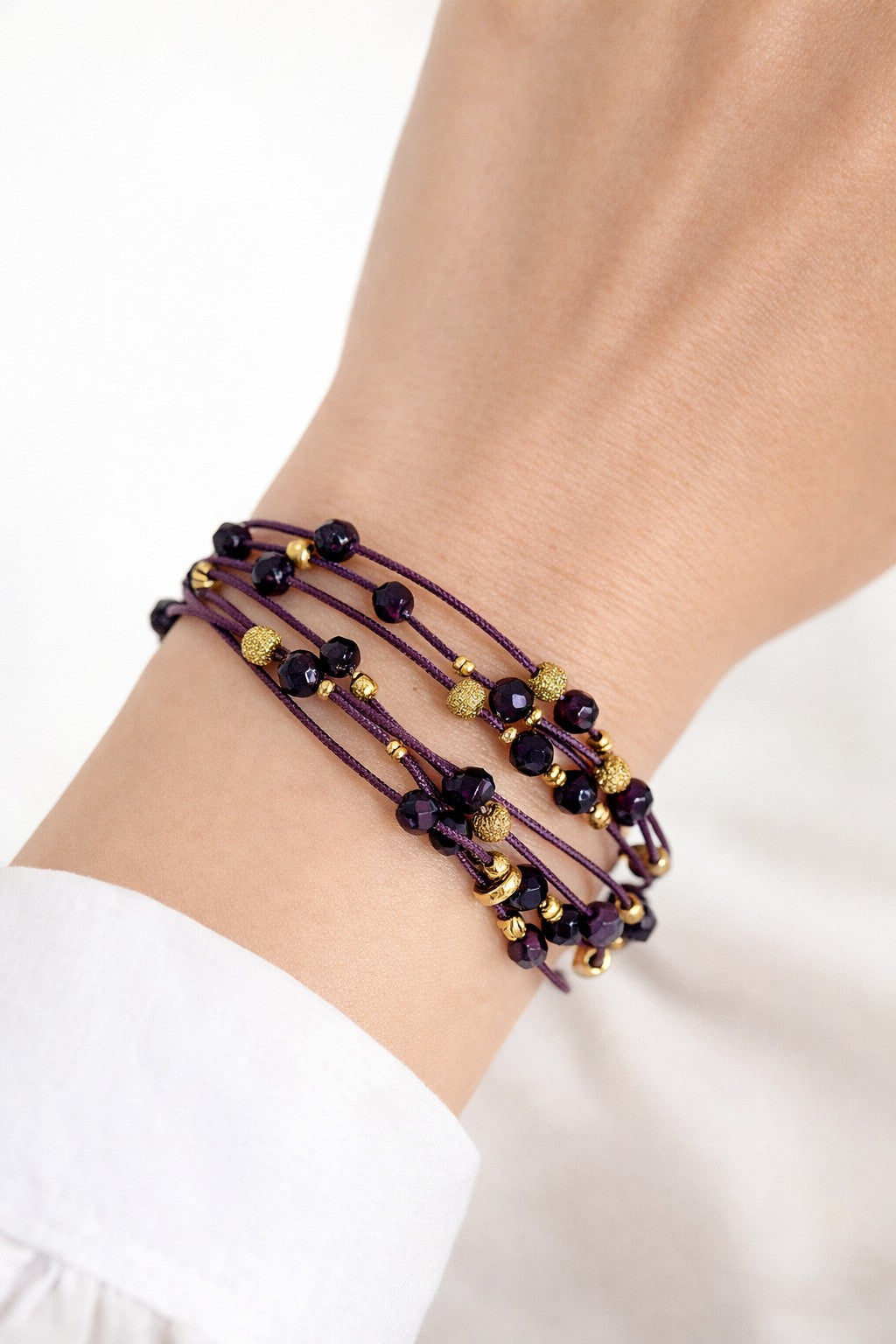 Pulsera granate de lino con cristal y acero dorado.