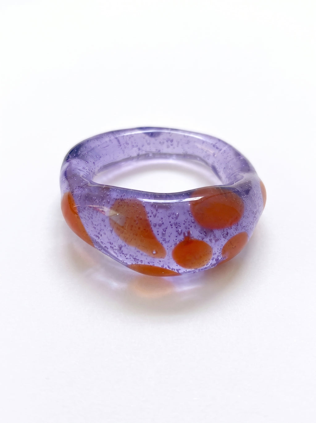 Anillo de vidrio morado translúcido con manchas naranjas