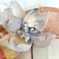 Tocado pamela de invitada en sinamay snaranjado, flores de seda azules y amarillas, con velo decorativo, elegante y colorido para boda.a