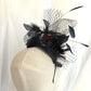 Tocado negro con flor de terciopelo rojo, plumas y velo decorativo, estilo elegante y vintage para invitada de boda.