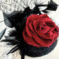 Tocado negro con flor de terciopelo rojo, plumas y velo decorativo, estilo elegante y vintage para invitada de boda.