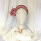 Diadema tocado en rosa palo con flores de organza, diseño elegante y romántico para invitada de boda o evento especial.