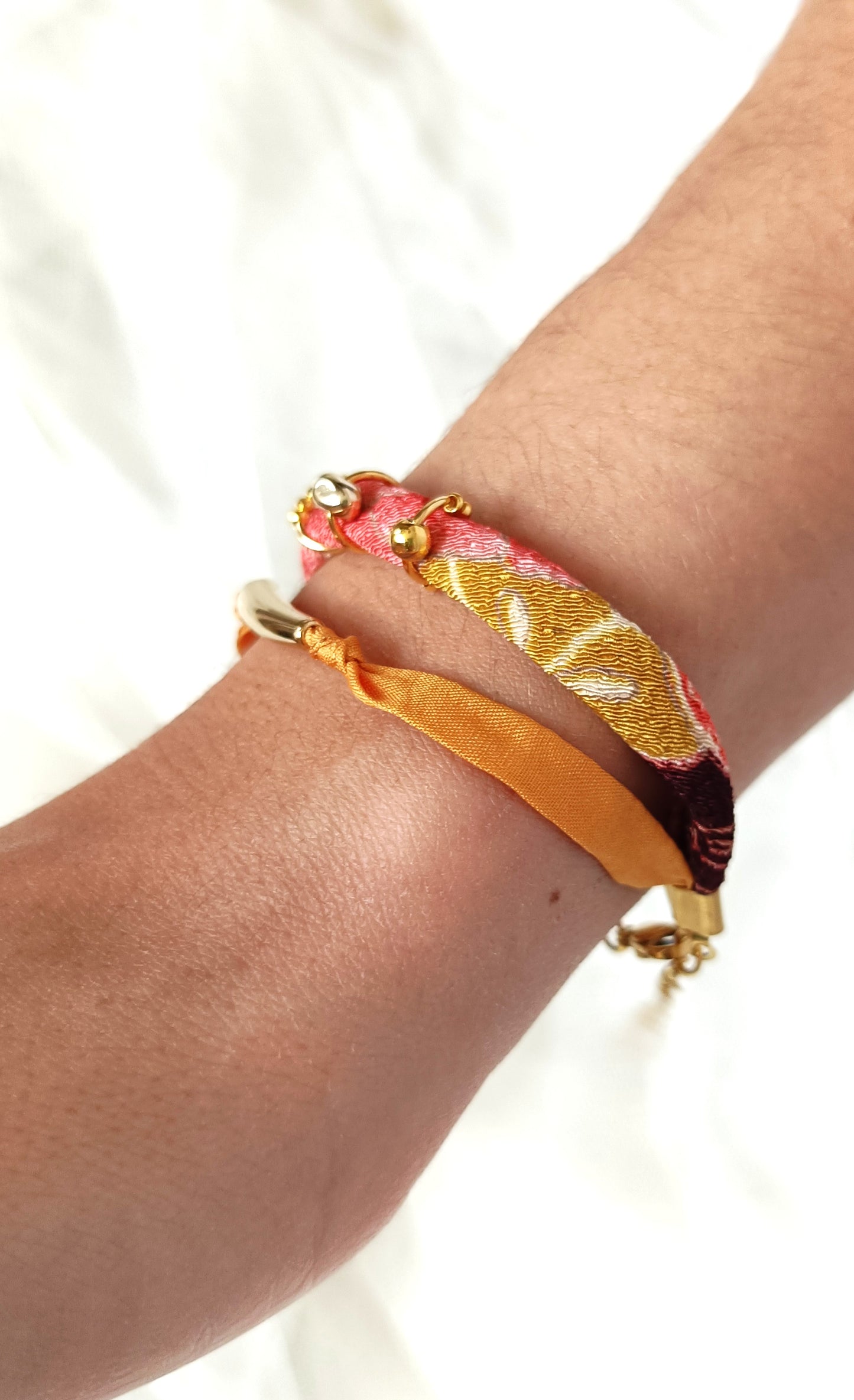 Pulsera doble de seda mostaza y cinta estampada con detalles dorados.