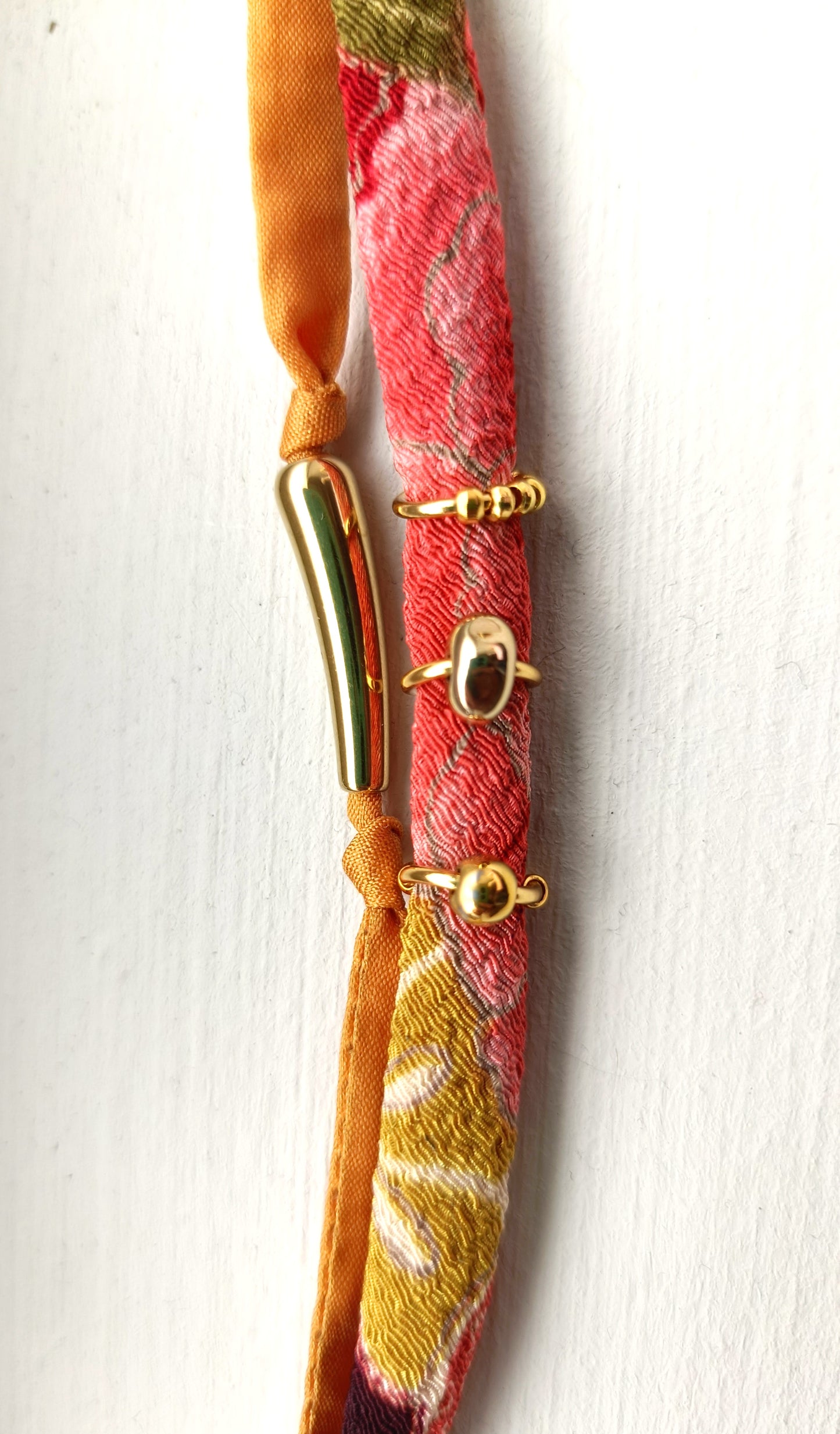 Pulsera doble de seda mostaza y cinta estampada con detalles dorados.