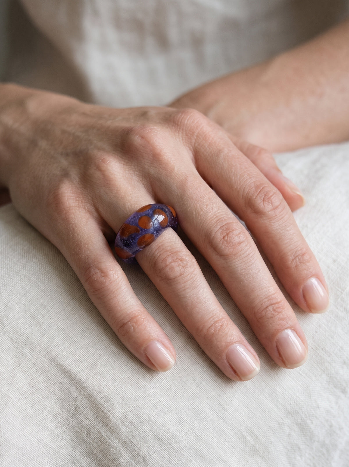 Anillo de vidrio morado translúcido con manchas naranjas