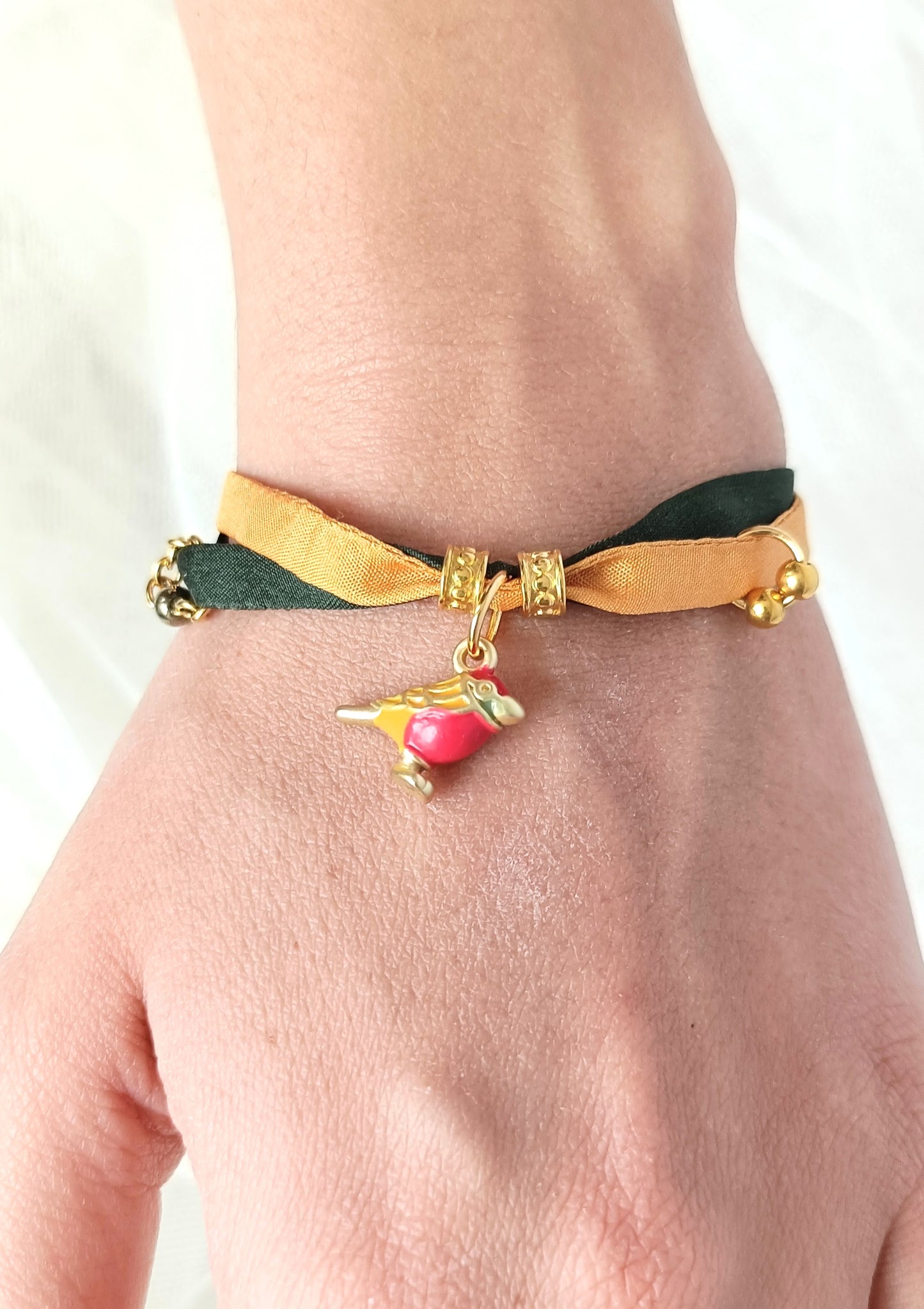 Pulsera de seda verde y mostaza con pajarita esmaltada