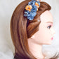 Diadema de flores de seda en azul y naranja, diseño elegante y romántico para invitada de boda o evento especial.