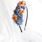 Diadema de flores de seda en azul y naranja, diseño elegante y romántico para invitada de boda o evento especial.