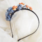 Diadema de flores de seda en azul y naranja, diseño elegante y romántico para invitada de boda o evento especial.