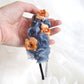 Diadema de flores de seda en azul y naranja, diseño elegante y romántico para invitada de boda o evento especial.